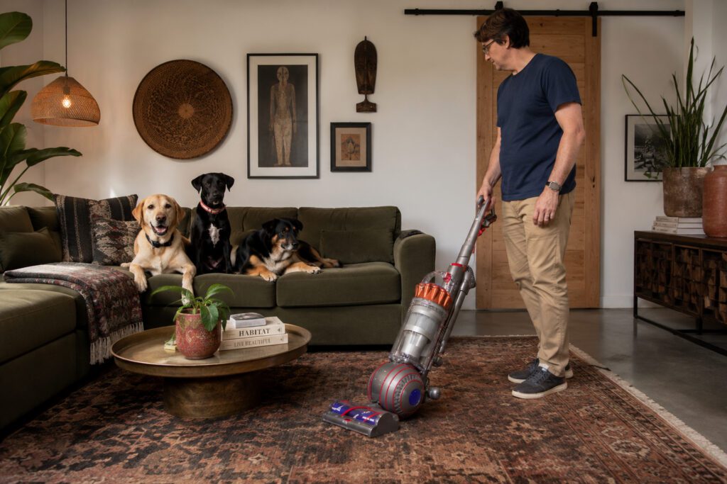 Man vacuums living room with Dyson Ball